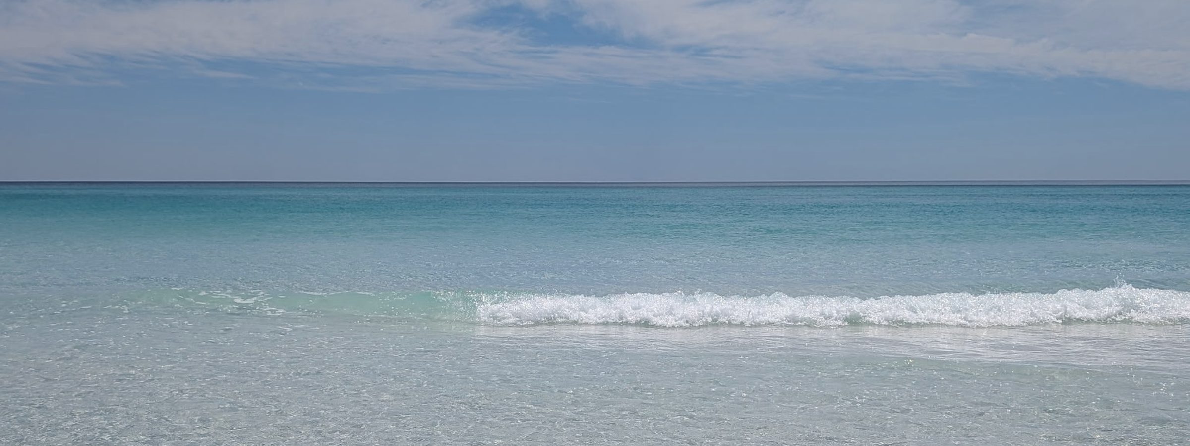 The Gulf on a clear day, one small wave breaking over white sand